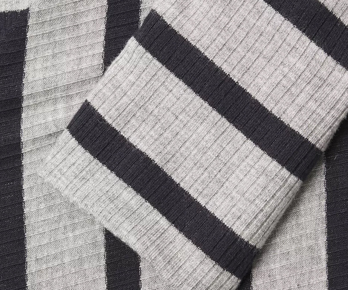 Undra Celeste New York Bias Stripe Knit Dress in Navy Grey, featuring bold diagonal stripes, a high turtleneck, voluminous long sleeves with fitted cuffs, a defined waist, and an asymmetrical midi-length hemline. Sophisticated contemporary women's workwear with modern geometric elegance.