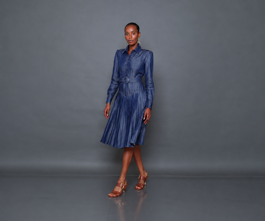 Undra Celeste New York Donna Pleated Dress in Soft Denim, crafted from soft Tencel denim, featuring a tailored button-front bodice, structured shoulders, long sleeves, a flattering V-shaped waist yoke, matching belt, and a flowing pleated midi skirt. Sophisticated contemporary women's workwear.