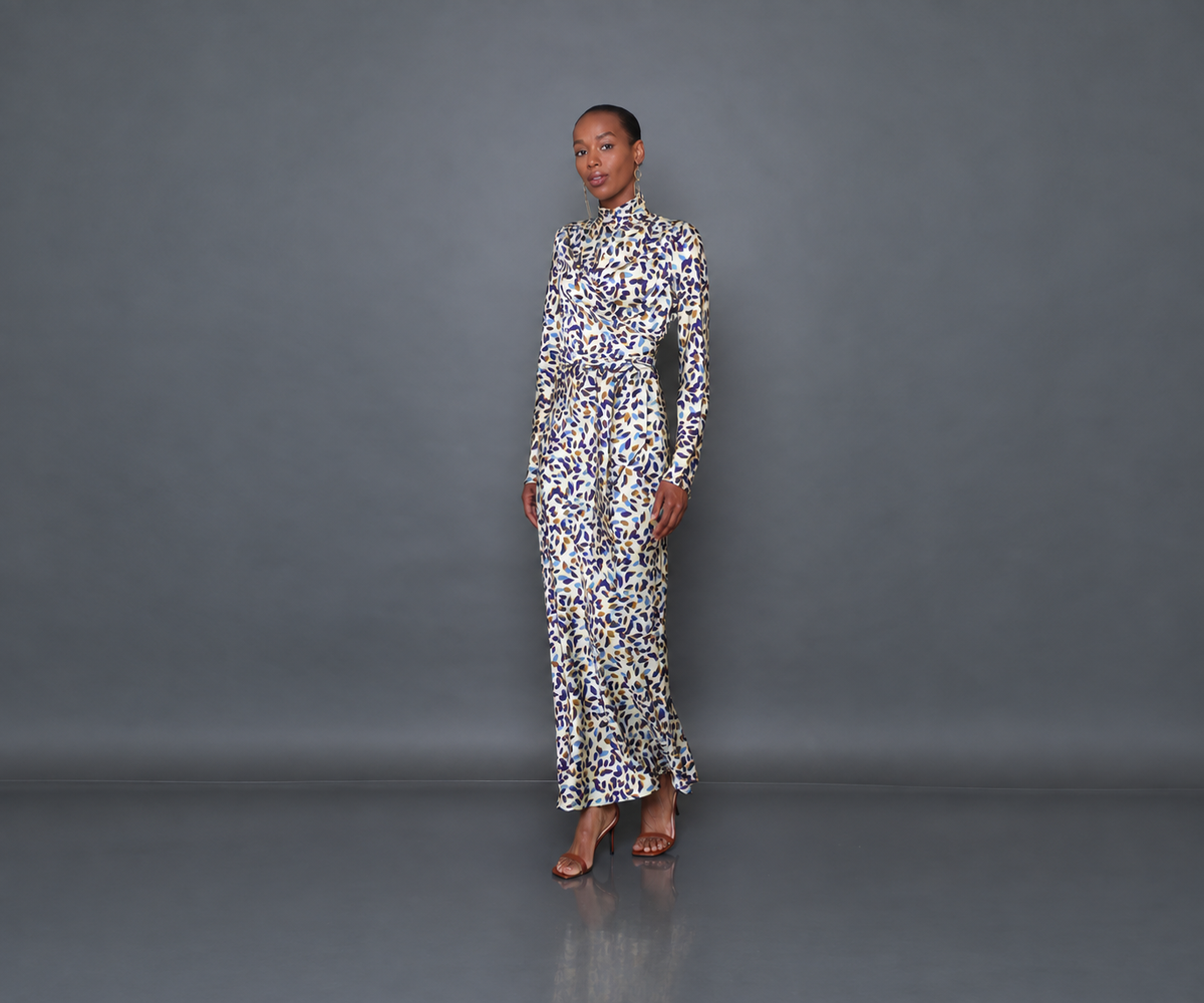 Undra Celeste New York Long Sleeve Mock Neck Joi Dress in Cream Falling Leaves print, crafted from luxurious hammered satin with a soft textured sheen, featuring a mock neckline, long flared sleeves, draped wrap-style bodice, defined waist, and flowing bias-cut maxi skirt. Sophisticated contemporary women's workwear.