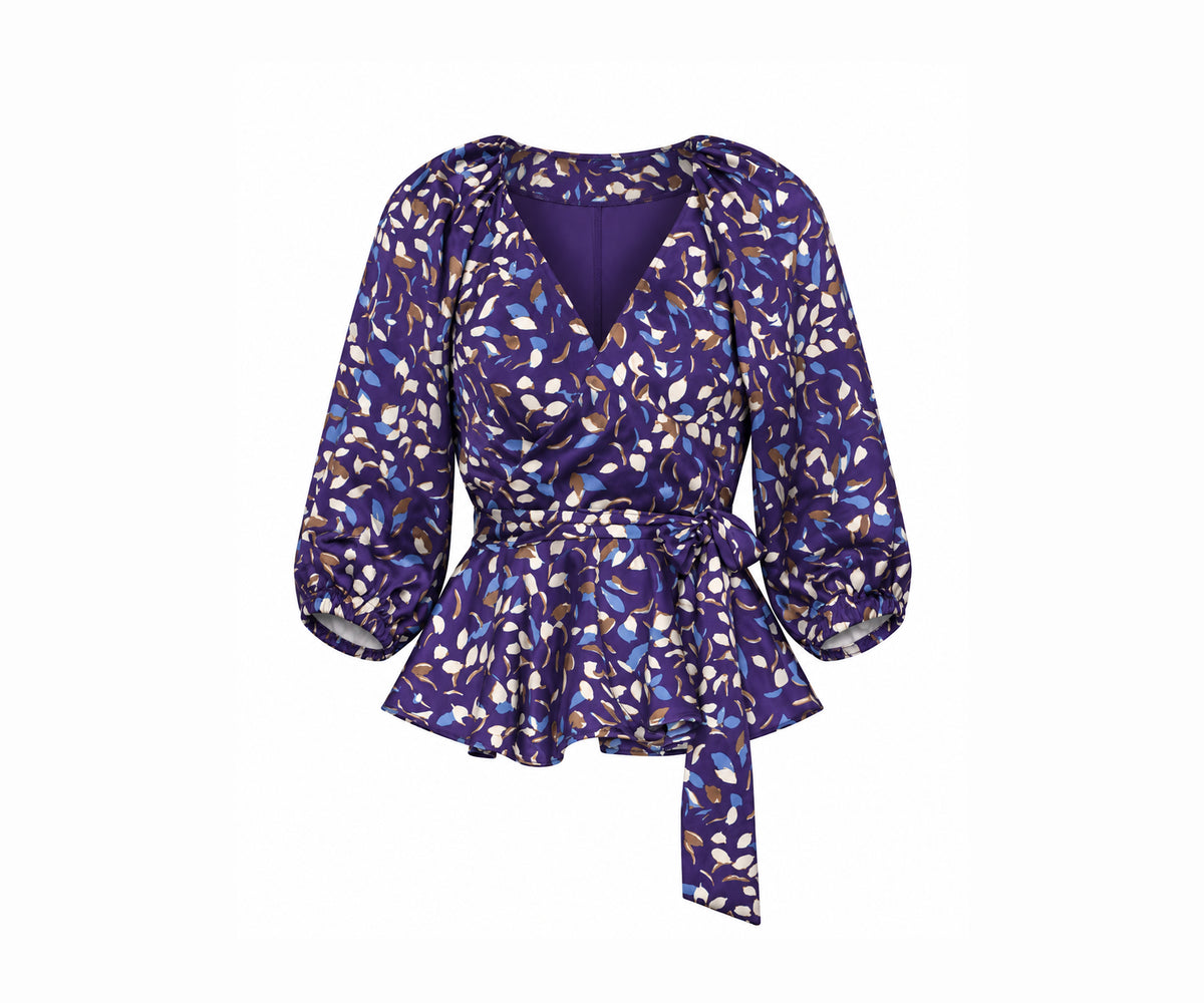 Undra Celeste New York Olivia Raglan Wrap Puff Sleeve Top in Purple Falling Leaves print, featuring luxurious hammered satin, a deep V-neckline, voluminous elbow-length puff sleeves, an adjustable wrap waist with an oversized tie sash, and a flared peplum hem. Elevated contemporary women's workwear.