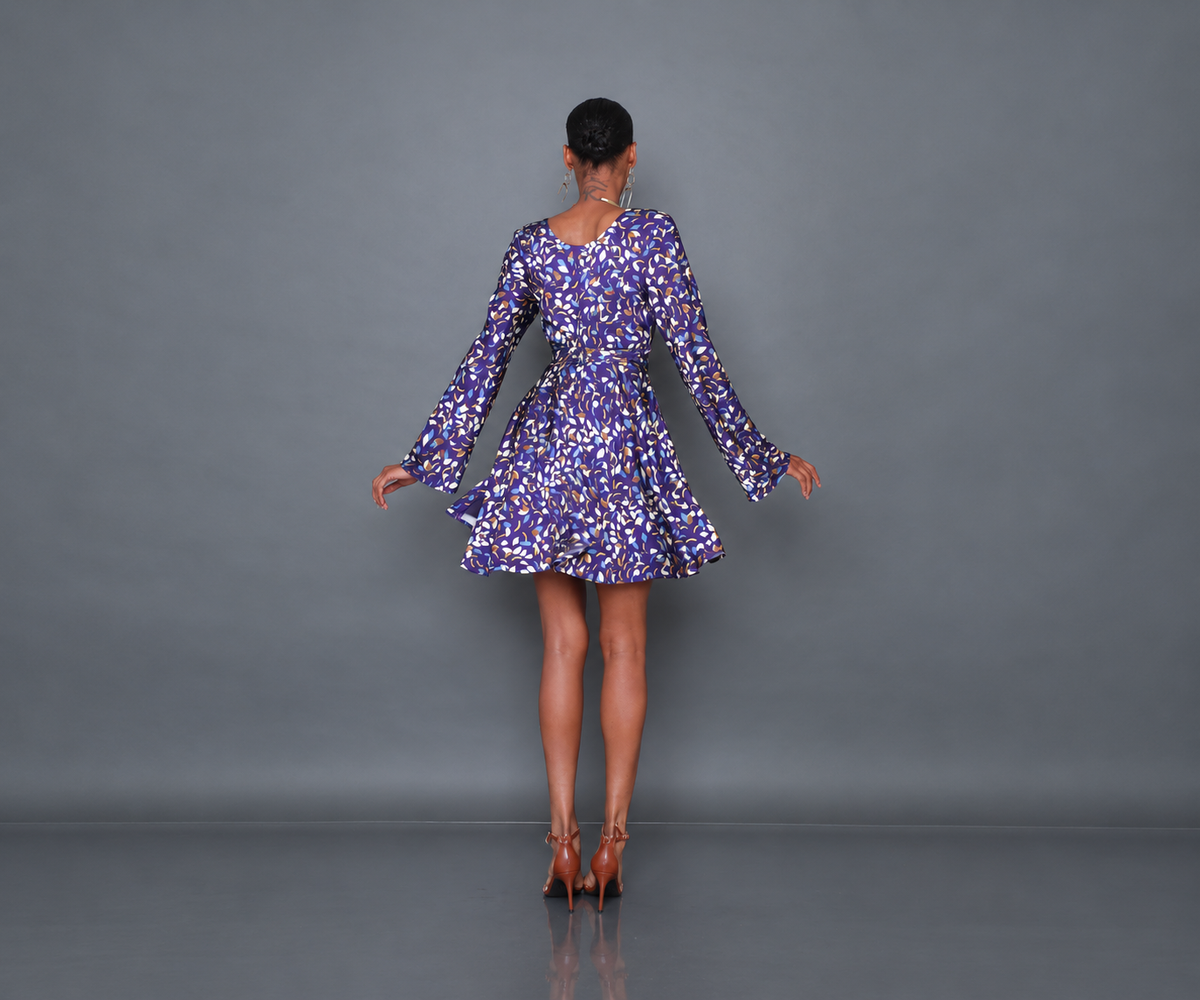 Undra Celeste New York Shonda Mini Wrap Dress in Purple Falling Leaves print, crafted from luxurious hammered satin with a deep V-neckline, long flared sleeves, adjustable wrap waist, oversized self-tie sash, and flowing mini-length skirt. Elevated contemporary women's workwear.