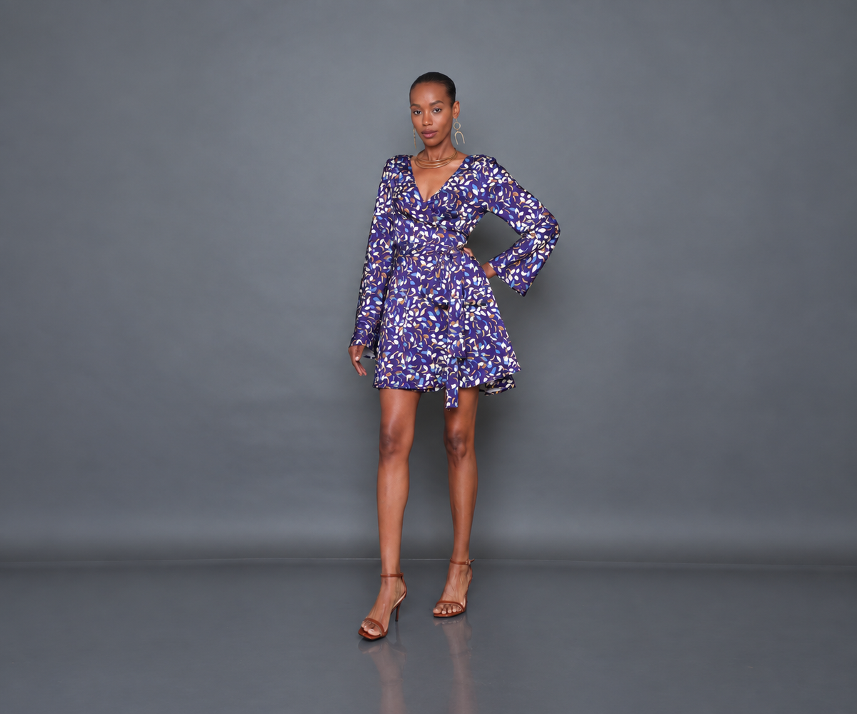 Undra Celeste New York Shonda Mini Wrap Dress in Purple Falling Leaves print, crafted from luxurious hammered satin with a deep V-neckline, long flared sleeves, adjustable wrap waist, oversized self-tie sash, and flowing mini-length skirt. Elevated contemporary women's workwear.