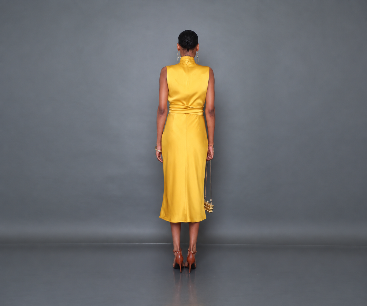 Undra Celeste New York Sleeveless Joi Dress in Taxi Yellow, featuring luxurious hammered satin, a high neckline, sleeveless wrap-style bodice, defined waist with adjustable tie sash, and flowing bias-cut skirt. Sophisticated contemporary women's workwear.